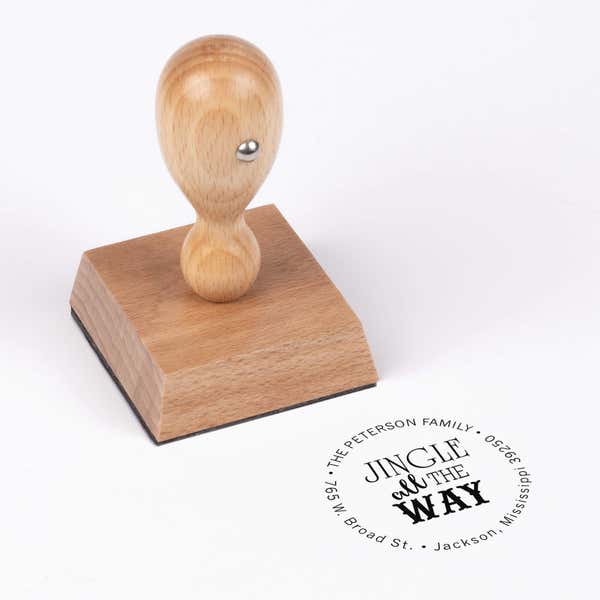 European wood hand stamp shown from above featuring custom ‘Jingle All The Way’ holiday return address design.