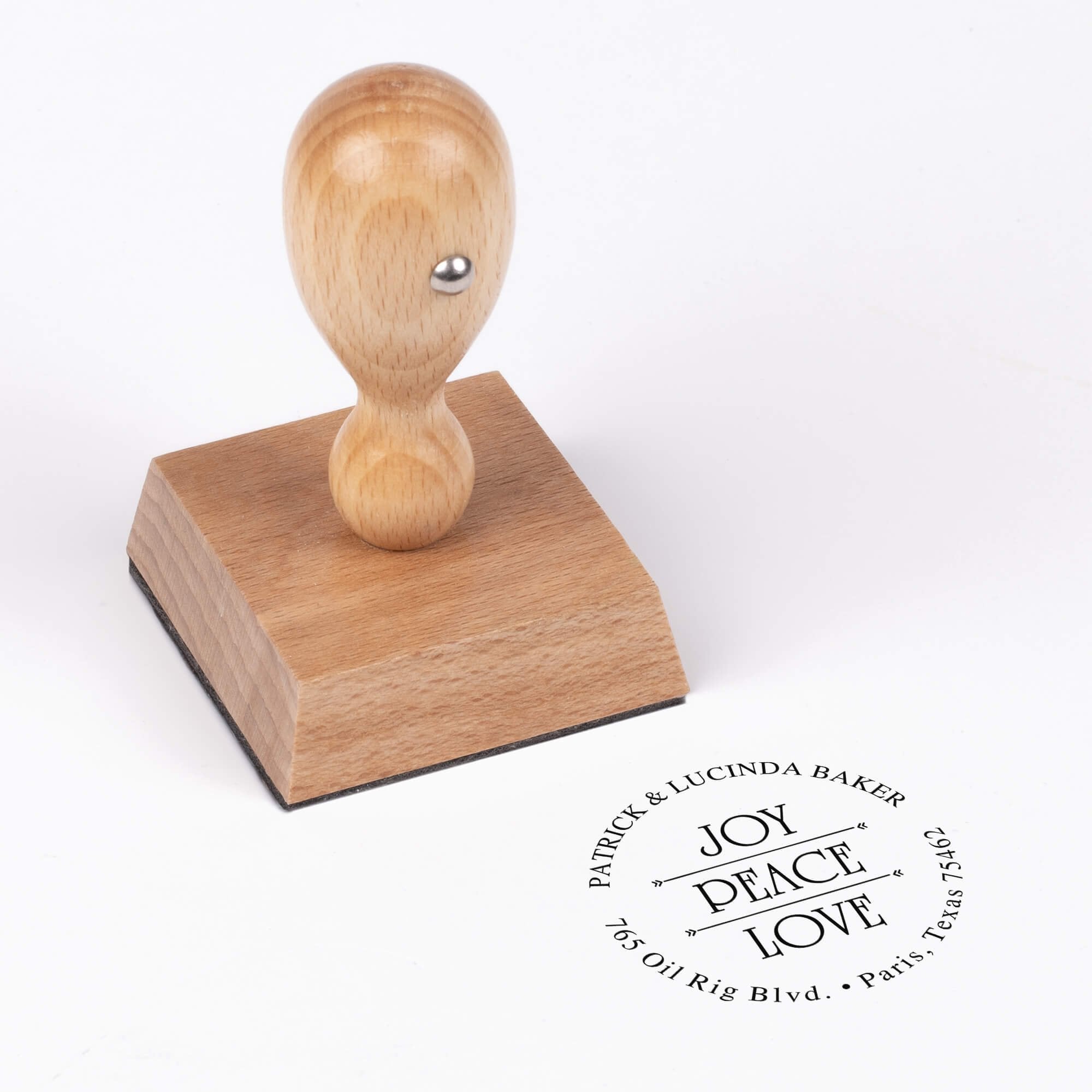 European wood hand stamp shown from above featuring custom ‘Joy Peace Love’ holiday return address design.