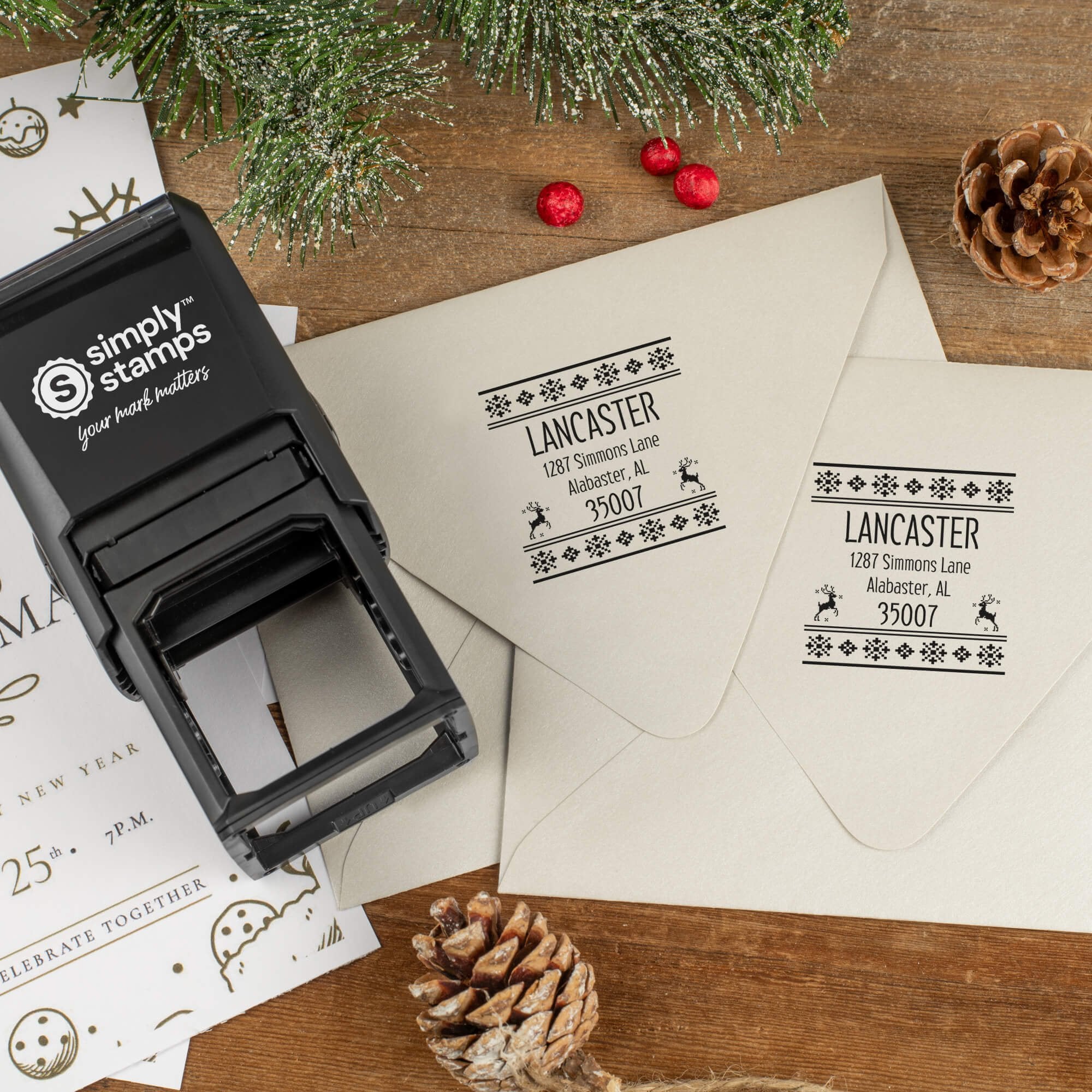 Holiday-themed ‘Designer Reindeer’ address stamp shown on envelopes beside festive stationery, pinecones, and decorations.