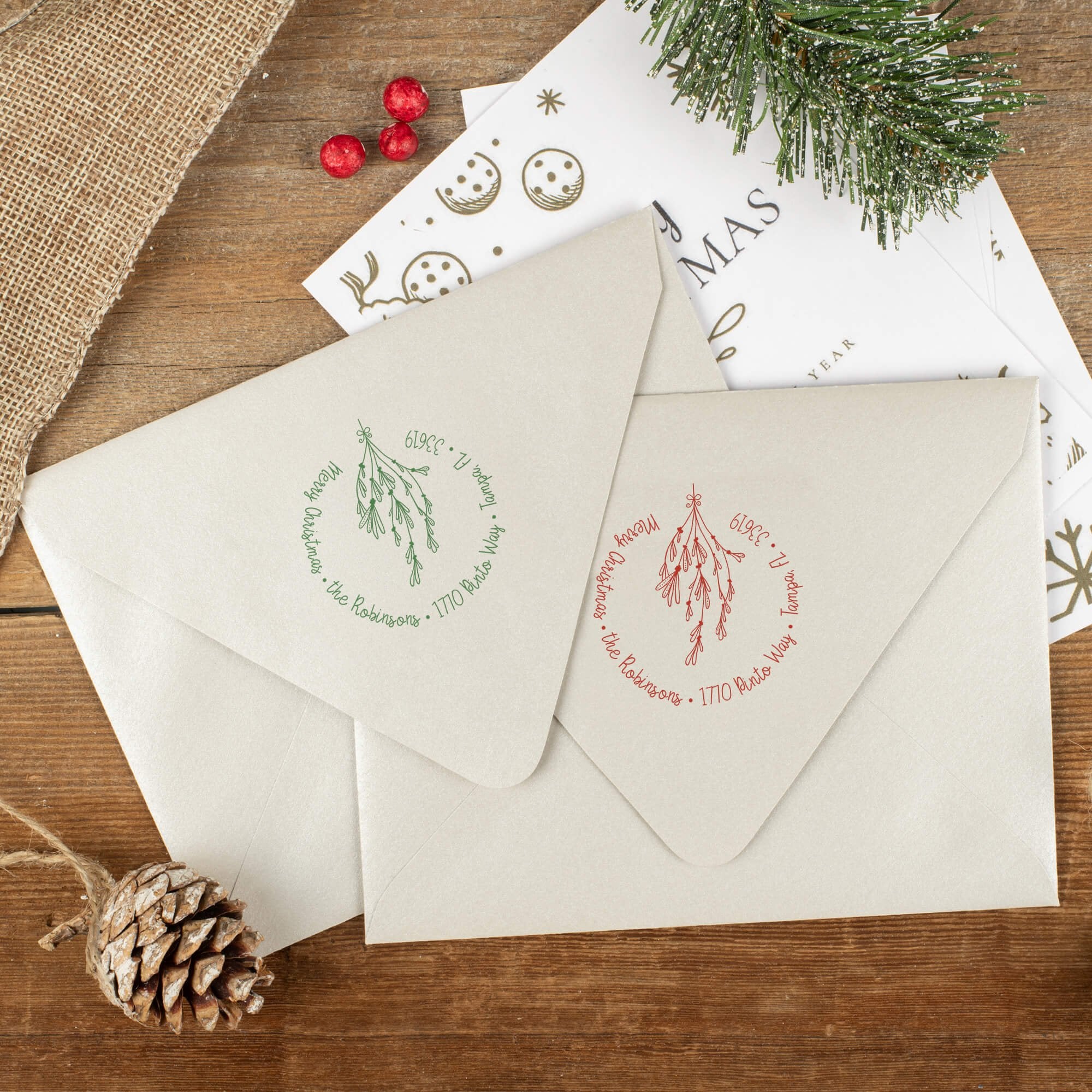 Green and red ink impressions of ‘Mistletoe Round Script’ return address stamp on Christmas envelopes.