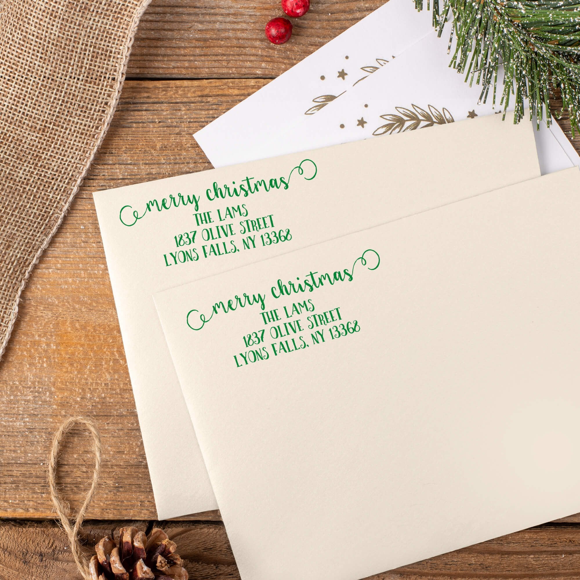 Green ink impressions of ‘Merry Christmas Decorative Swirl’ return address stamp on Christmas envelopes.