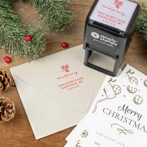 Holiday-themed ‘Montgomery Pine Winter’ address stamp shown on envelopes beside festive stationery, pinecones, and decorations.