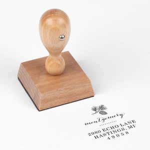 European wood hand stamp shown from above featuring custom ‘Montgomery Pine Winter’ holiday return address design.
