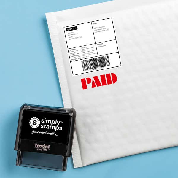 Red “PAID” stamped on a white padded mailer; self-inking office stamp shown beside the package