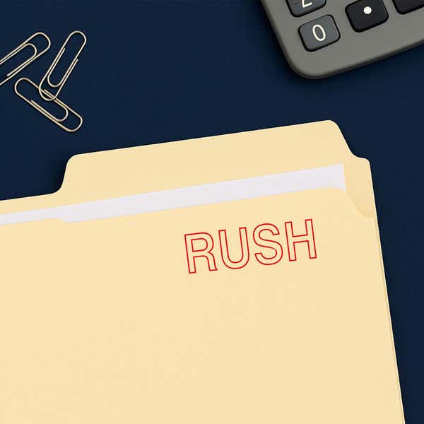 Red outline RUSH stamped on a manila file folder beside office supplies