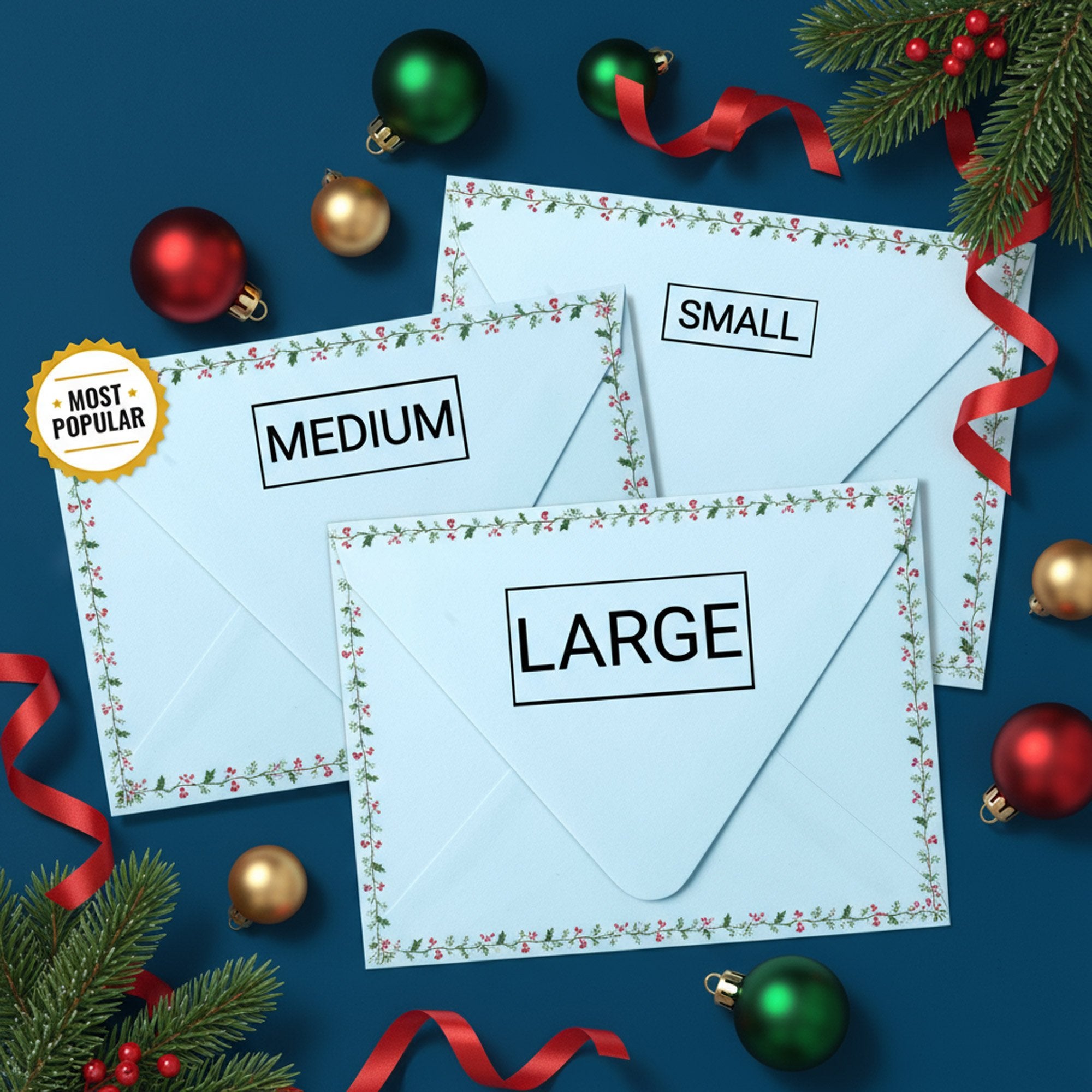Holiday-themed envelopes displaying small, medium, and large self-inking stamp impression sizes surrounded by ornaments and ribbon.