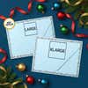 Comparison image showing large and extra-large self-inking stamp impression sizes on blue holiday envelopes with ornaments and ribbon.