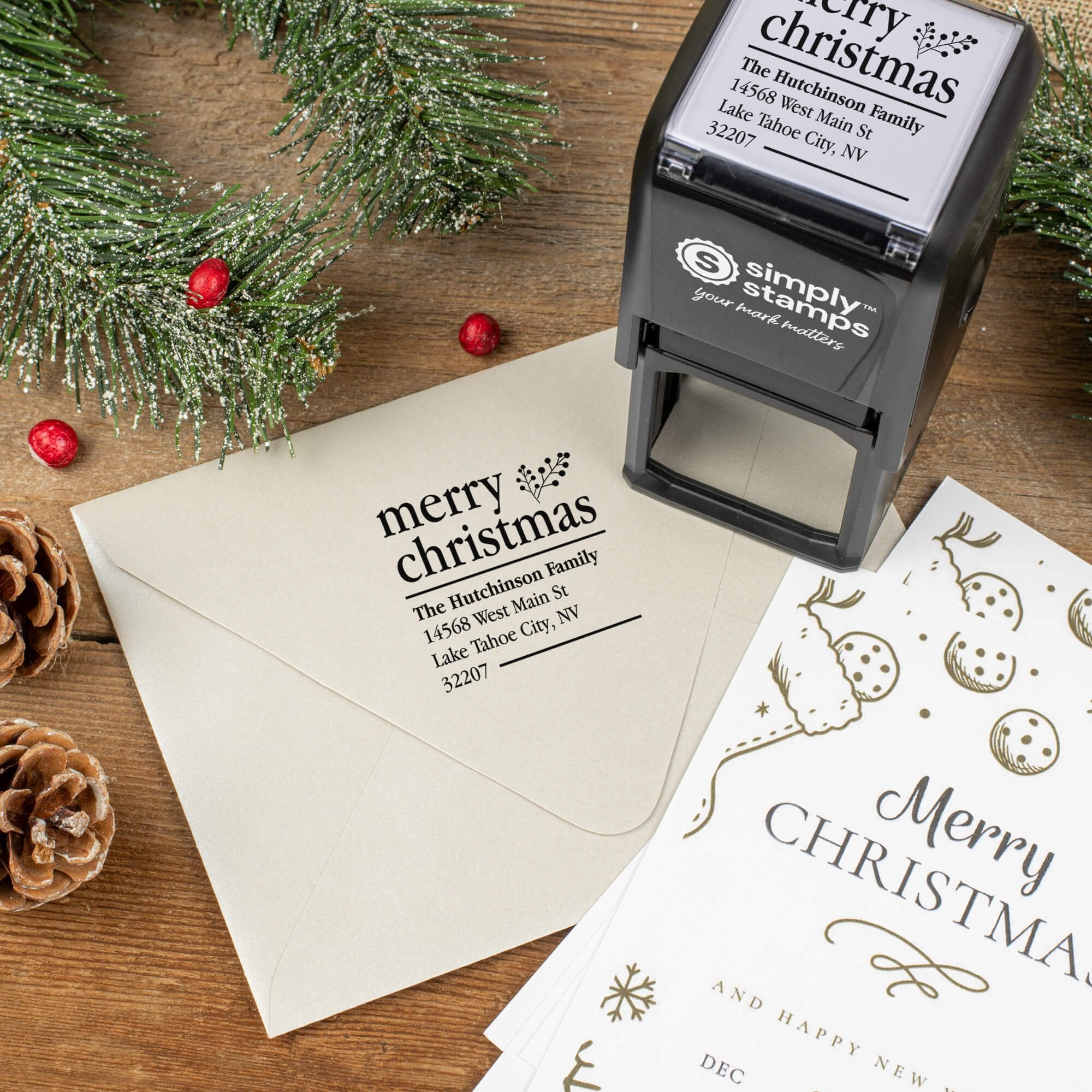 Holiday-themed ‘Merry Christmas With Fern’ address stamp shown on envelopes beside festive stationery, pinecones, and decorations.