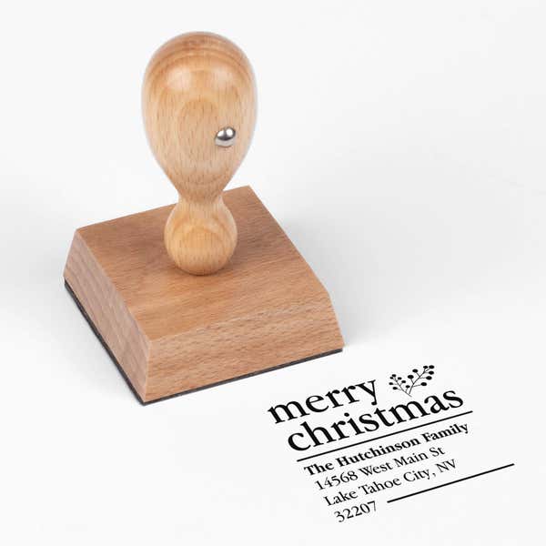 European wood hand stamp shown from above featuring custom ‘Merry Christmas With Fern’ holiday return address design.