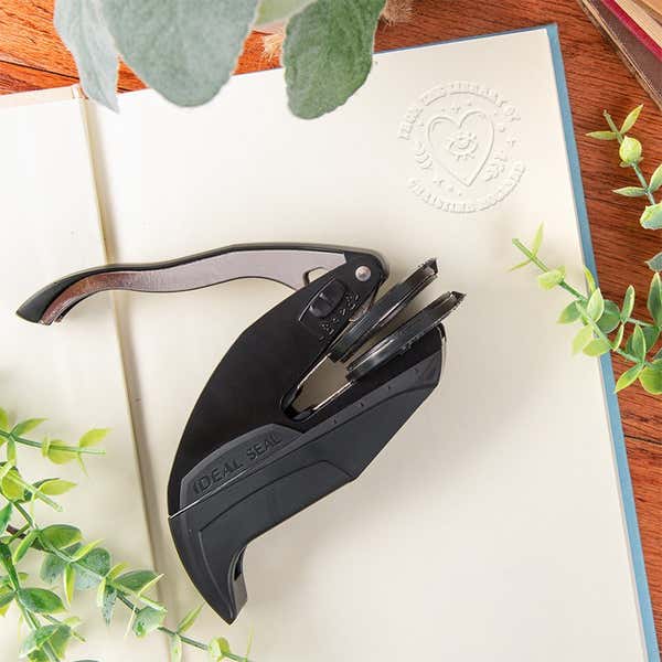 Personalized book embosser stamp on it’s side with book