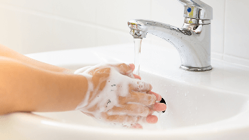 Image of a child washing their hands with soap and water over a sink