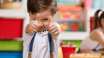 Image of a kid giving two thumbs up at school